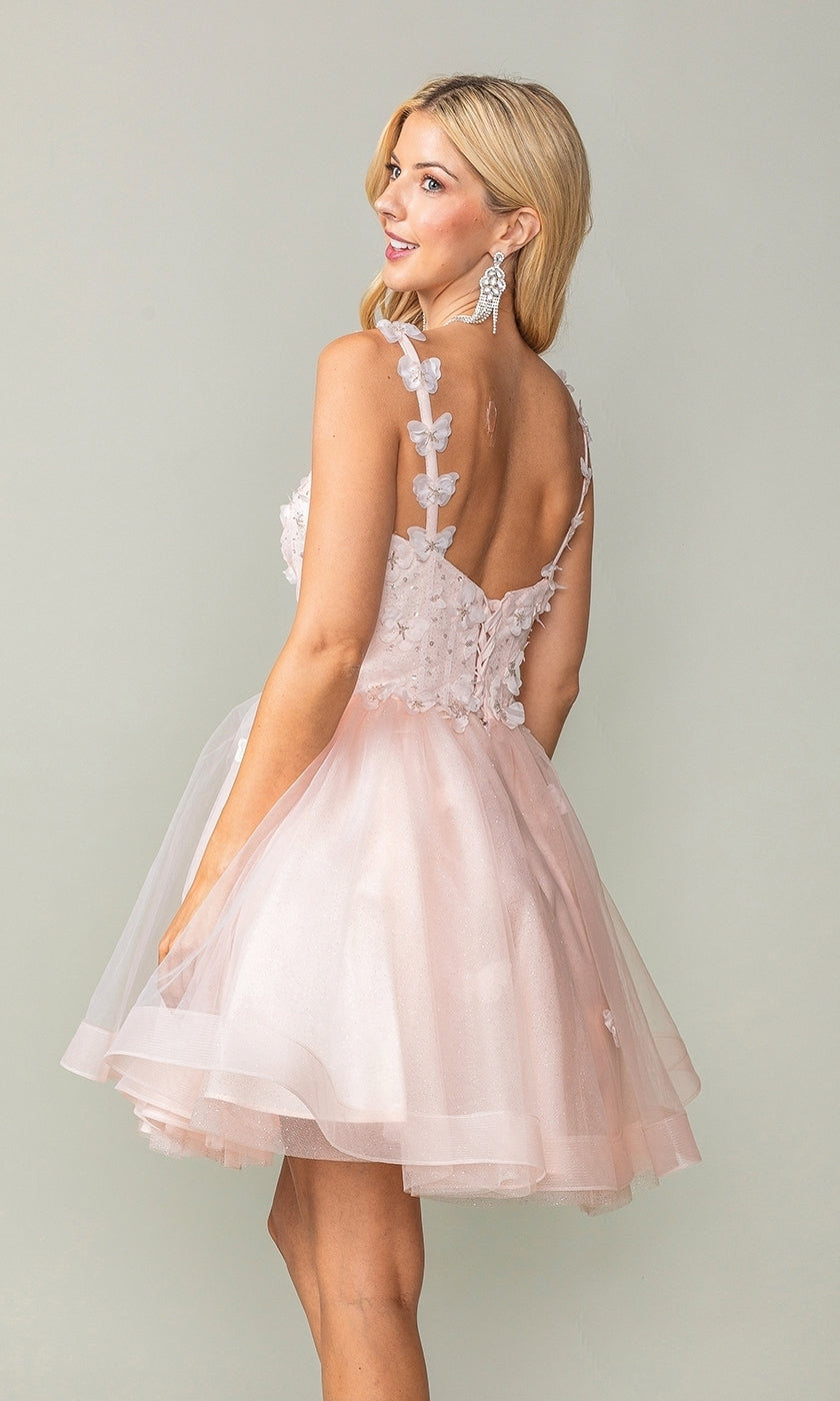 Wearing the Lace-Up Short Butterfly Homecoming Dress 3369, a woman in a light pink sleeveless dress with 3-D butterflies and floral appliqués stands slightly turned, revealing its open back and layered tulle skirt.